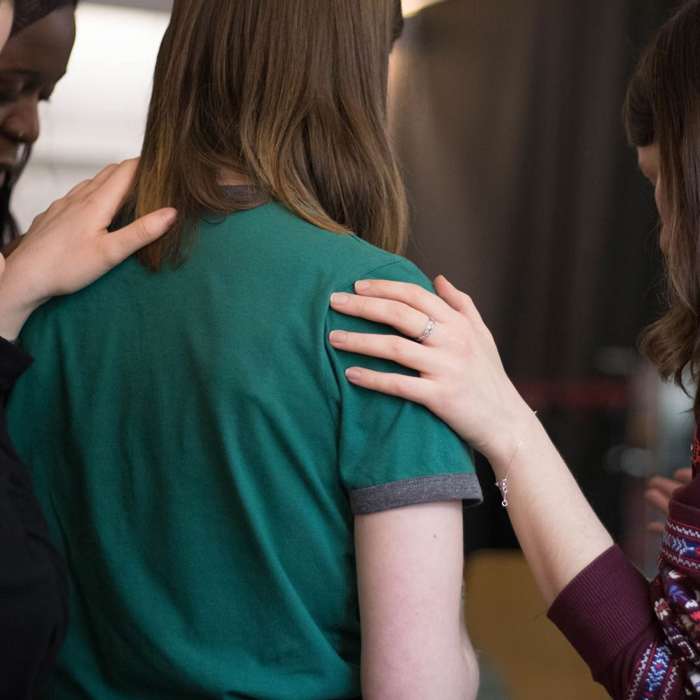 a group of women praying over someone